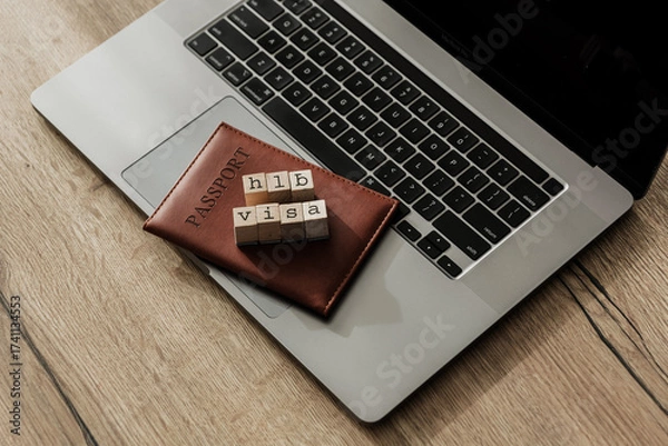 Fototapeta H1B visa wooden blocks on passport and laptop, symbolizing U.S. work permit