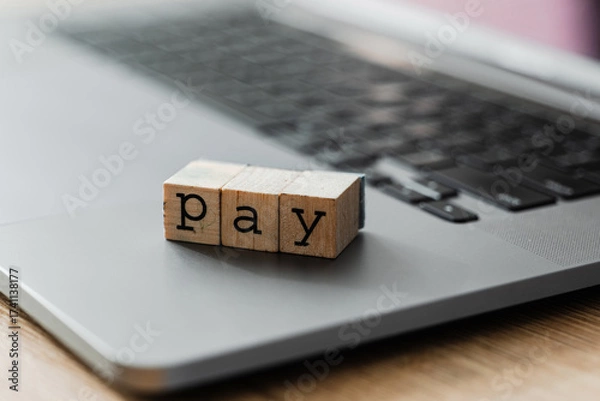 Fototapeta Wooden blocks spelling PAY on laptop keyboard, concept of digital payment