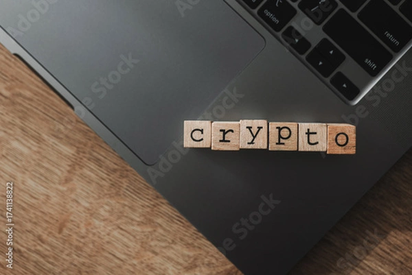 Fototapeta Wooden blocks forming the word “crypto” on a laptop keyboard, representing cryptocurrency, blockchain, digital assets, fintech innovation, and online financial transactions