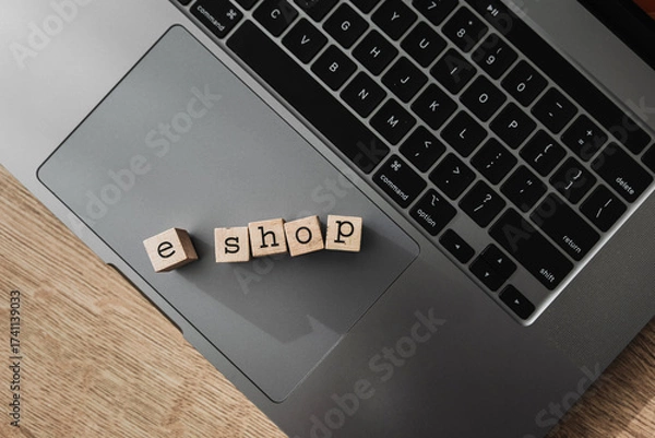 Fototapeta Wooden blocks spelling e shop on laptop, concept of online store and modern e-commerce platform
