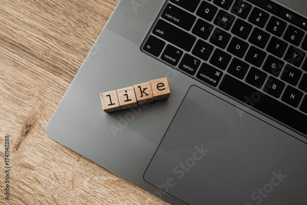 Fototapeta Wooden blocks spelling LIKE on laptop, concept of social media engagement, digital approval, and online interaction