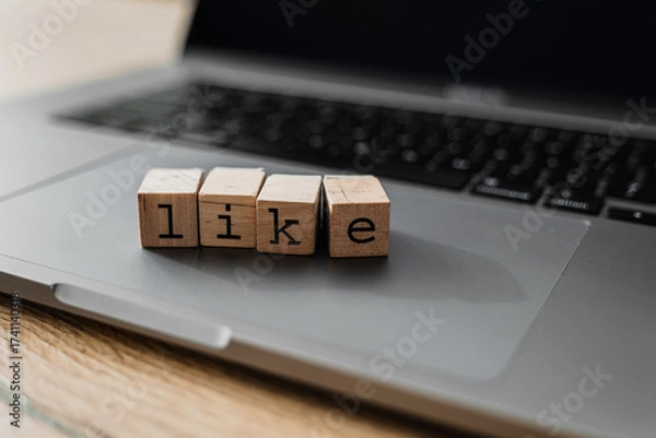 Fototapeta Wooden blocks spelling LIKE on laptop, concept of social media engagement, digital approval, and online interaction