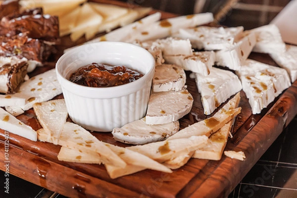 Fototapeta Rustic wooden board presenting sliced goat cheese and a ramekin of fig jam, creating a gourmet appetizer