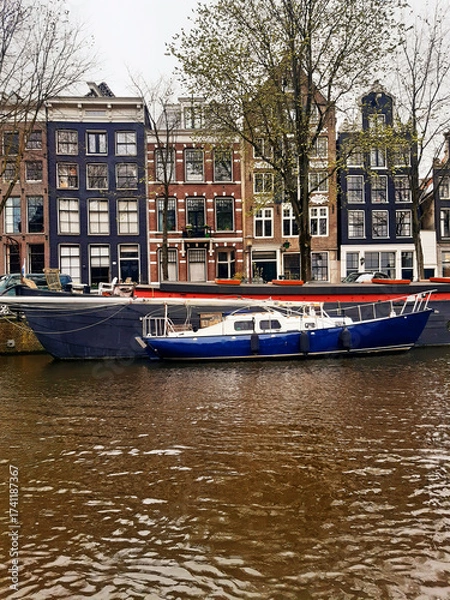 Fototapeta Panoramic view of Dutch facades, houseboats, and boats in the canals on a gray, overcast day. Urban planning and culture of the Netherlands.