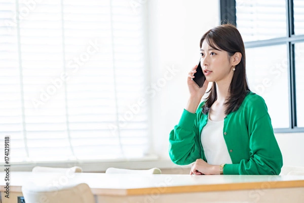 Fototapeta 明るい室内で通話をする女性