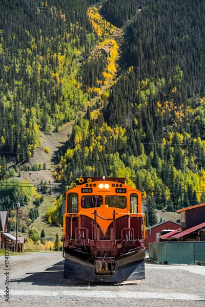 Fototapeta Durango and Silverton narrow gauge steam engine train stop in front of a beautiful mountain view during early fall foliage in Silverton town. Classic railroad transport in Colorado, USA.