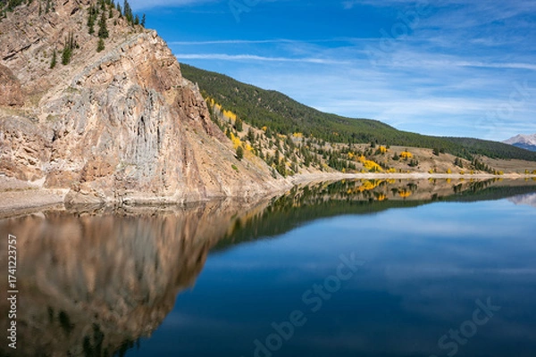 Fototapeta Pine forest on mountain against the blue sky reflect in the water at Taylor park reservoir, A huge lake near Almont in Colorado, USA