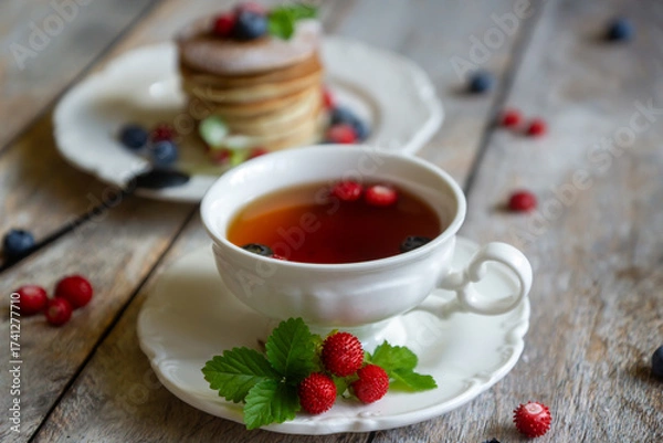 Fototapeta Delicate pancakes with fruits and berries on a wooden table.