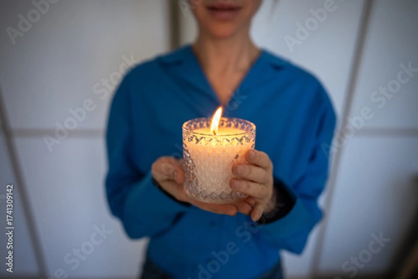 Fototapeta Unrecognizable woman holding scented candle with essential oils for meditative stress relief. Aromatherapy benefits, natural remedies, calming environment, holistic wellness, self care routine.