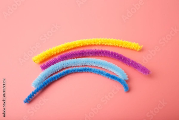 Fototapeta Colorful pipe cleaners on pink background in curved layout, ideal for preschool education, craft supply branding, sensory play visuals, early learning materials, and DIY activity promotion