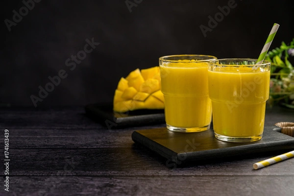Fototapeta Mango banana smoothie in a glass with fresh fruit, black background, copy space