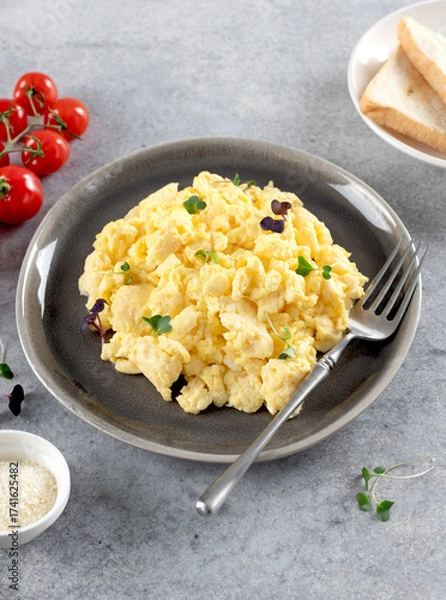 Fototapeta Scrambled eggs with green onions, tomato, cheese on a gray plate on gray background. Healthy breakfast. 
