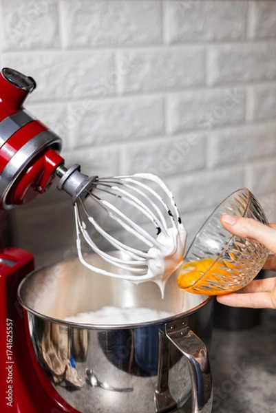 Fototapeta Pastry chef adding egg yolk in the red mixer bowl. Preparing cooking for dinner guests