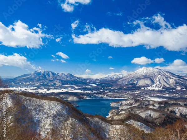 Fototapeta A stunning winter view of the blue Lake Nojiri and the snow-capped mountains of Iizuna and Kurohime (viewed from Madarao, Nagano, Japan)