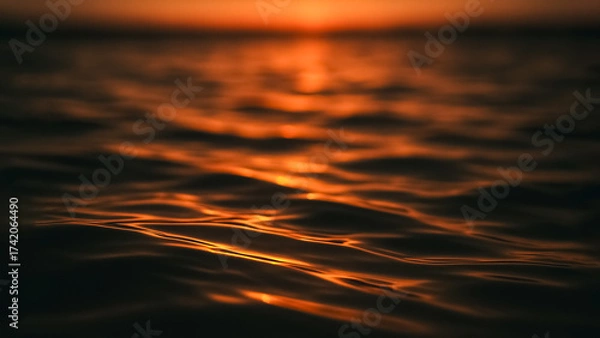 Fototapeta The serene waters of the ocean are ablaze with the fiery hues of sunset, with the sun's reflection painting the water surface with shades of orange and gold.