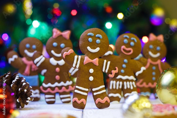 Fototapeta Festive christmas background with gingerbread men. Gingerbread mans on a bright christmas background. Happy New Year festive background 