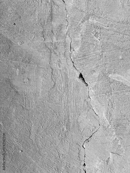 Fototapeta Dramatic black and white shot: a wide, winding crack cutting across the rough, shadow-covered surface of an old wall.