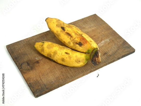 Fototapeta Ripe Bananas on Rustic Wooden Cutting Board Isolated on White