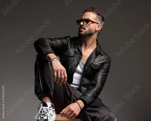 Obraz confident cool man with sunglasses looking to side and sitting with elbow on knee