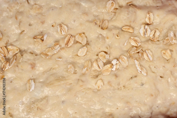Fototapeta A close-up captures the textured surface of raw bread dough dotted with rolled oats before baking