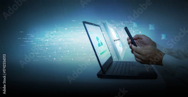 Obraz Hand of businessman using mobile phone and laptop computer with high tech background. Approval of a digital online purchase transaction or digital identity verification.