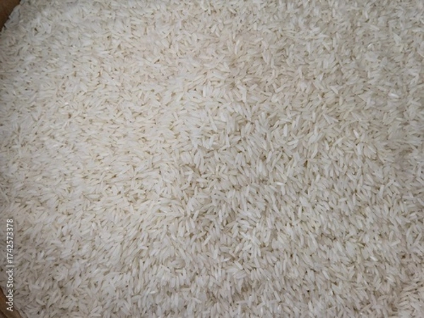 Fototapeta Close-up, high-angle, full-frame shot of uncooked long-grain Jasmine rice, showing slender, elongated, slightly translucent white kernels.