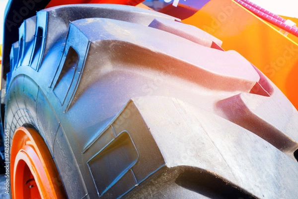 Fototapeta Tire for loader close-up. Heavy Machinery Tire background in Bright Sunlight. Close-up large rugged tire for heavy machinery. New rubber tire with tread for special construction wheeled vehicles.