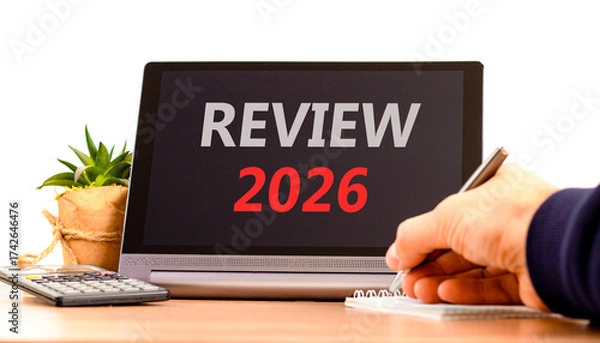 Fototapeta Review 2026 symbol. Concept words Review 2026 on beautiful black tablet screen. Beautiful white background. Businessman's hand. Business and review 2026 concept. Copy space.