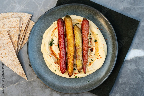 Obraz Creamy hummus served with baked carrot, perfect for healthy snack.