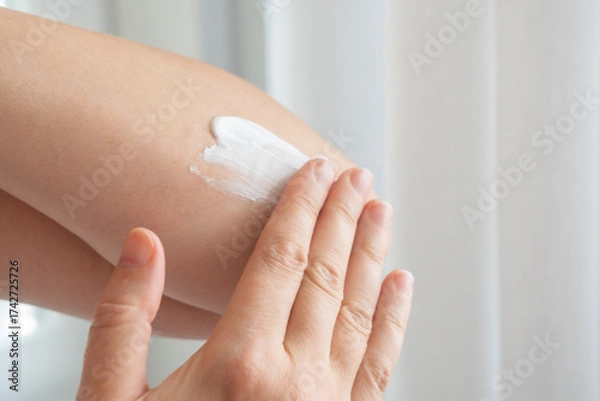 Fototapeta Cream on elbow skin. Applying the lotion to dry rough hands skin, elbow moisturizing creme