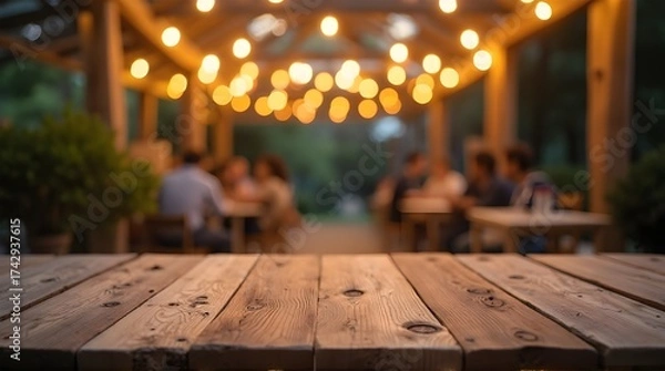Obraz Rustic wooden table at a charming outdoor restaurant with friends dining under warm string lights, perfect for a summer evening gathering