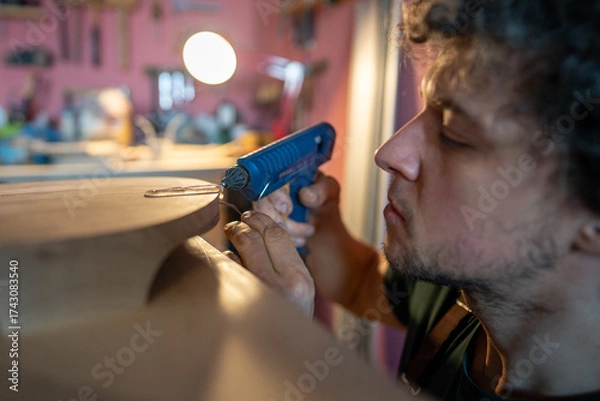 Fototapeta Woodworker applying molten silicone along edges of split in wood surface to contain future resin pour. Crack repair, prevent split expansion, restoration, functional fix for timber flaw, artisan work