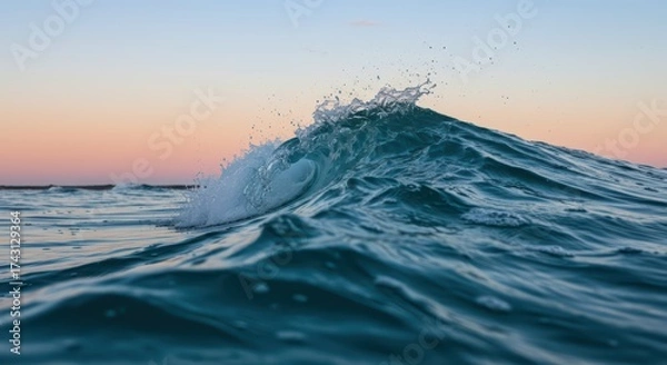 Obraz Close up view of a clear blue wave crashing and spraying water in the ocean at sunrise or sunset. Powerful liquid motion and serene nature scene. World Oceans Day.