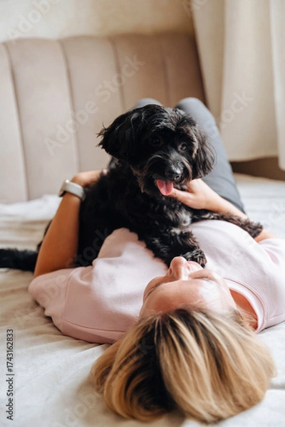 Fototapeta Woman relax on couch with puppy, happy and content at home with pet
