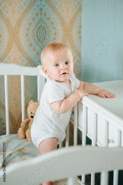 Fototapeta Portrait of a 8 month old crawling baby on the bed. the baby smiles and looks at the camera