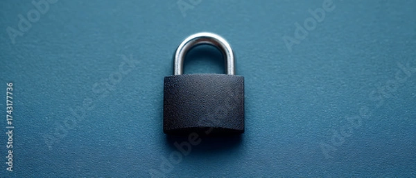 Fototapeta Secure Black Padlock Resting on a Smooth Blue Surface in a Minimalist Setting Emphasizing Protection and Safety