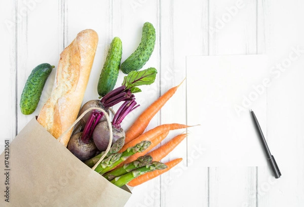 Fototapeta Paper shopping bag with fresh bread and vegetables. Flat lay, top view