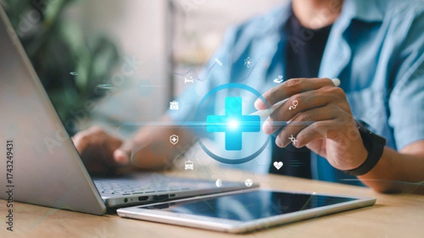 Fototapeta Medical technology concept. Close-up of person using laptop and tablet with digital healthcare icons overlay. Concept for telemedicine, health data, and digital innovation.