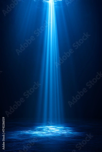 Fototapeta Mystical beams of radiant blue light pierce the darkness over a tranquil ocean surface.