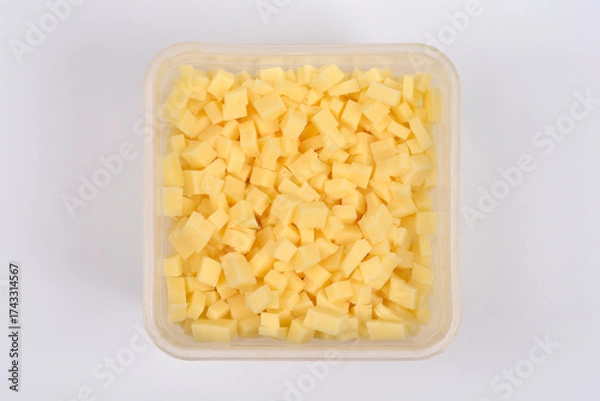 Fototapeta An overhead shot features a transparent, square container completely filled with yellow cheese cubes, centered on a plain white background