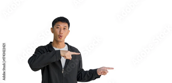 Fototapeta Shocked face young Asian man in black coat pointing thumbs up isolated on a white background. The person's index finger pointing to a blank space for text