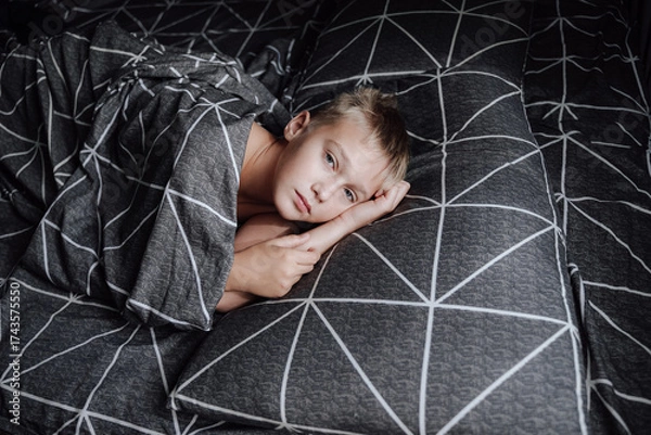 Obraz A handsome blond boy is lying in bed