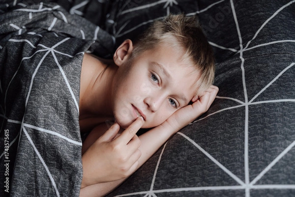 Obraz A handsome blond boy is lying in bed