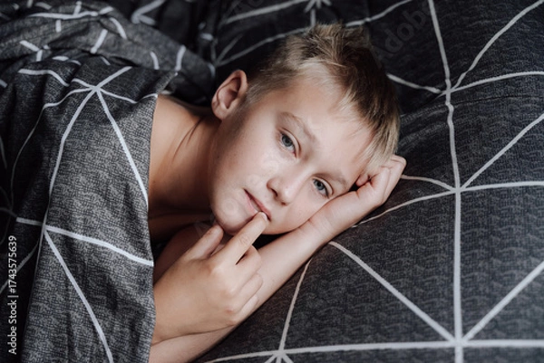 Obraz A handsome blond boy is lying in bed