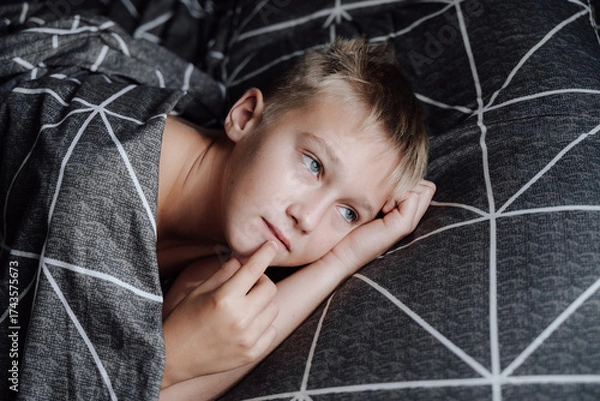 Obraz A handsome blond boy is lying in bed