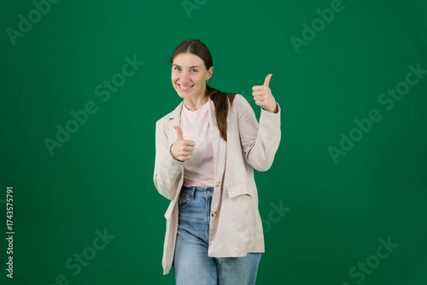 Fototapeta Professional photo collection of young European woman in light blazer with hair tied in ponytail and blue jeans on green chroma key background expressing different emotions and gestures perfect for ad