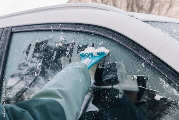 Fototapeta unrecognizable person scraping ice from car window on cold winter day