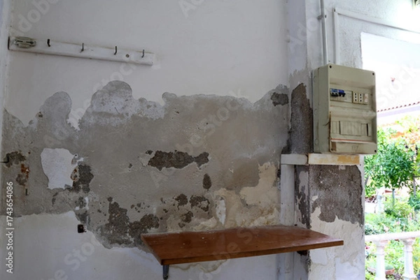 Obraz Severely Damaged Wall with Plaster Loss and Moisture Stains Caused by Rising Capillary Damp, Highly Dangerous Due to Nearby Electrical Panel