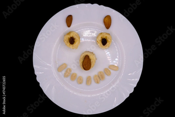 Fototapeta Delightful dessert creation with playful face using fruits and nuts on a white plate during a cheerful gathering