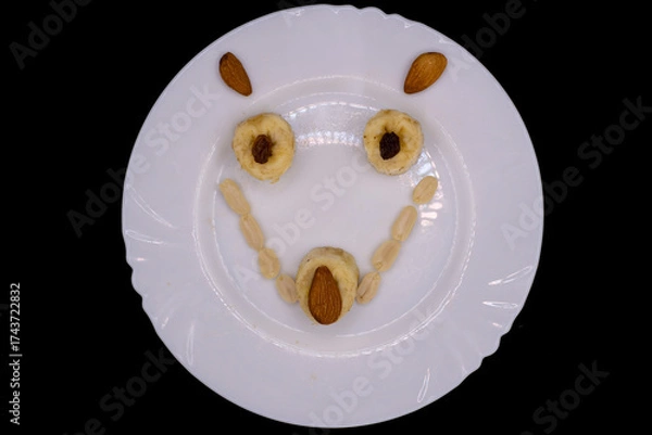 Fototapeta Creative food art using fruits and nuts to create a smiling face on a white plate